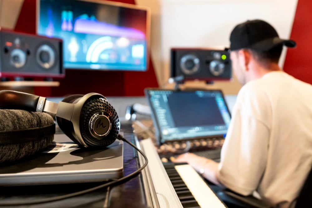 Image of Focal Lensys on music equipment in a studio room, with a music producer in the background